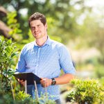 Gardener holding a clipboard, in his garden, green sunny nature